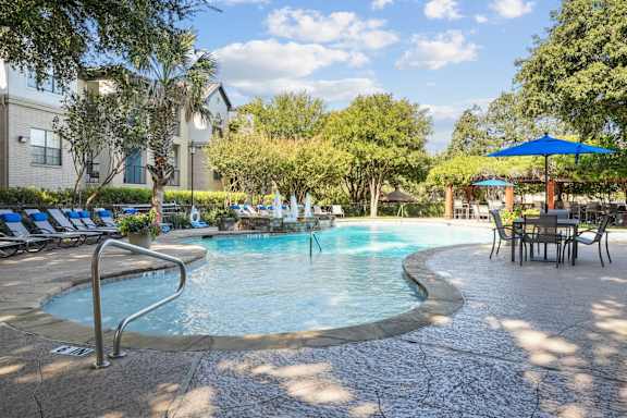 a swimming pool with chairs and umbrellas at the resort on a sunny day
