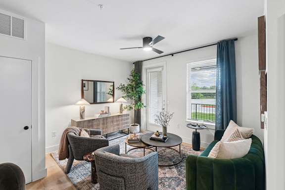 A living room with a grey couch, a green couch, a coffee table, and a ceiling fan.