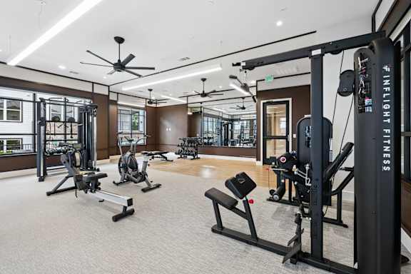 A gym with a variety of equipment including a squat rack, a bench, and a treadmill.