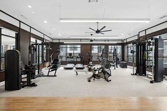 A spacious gym with a variety of equipment including treadmills, stationary bikes, and weight machines.