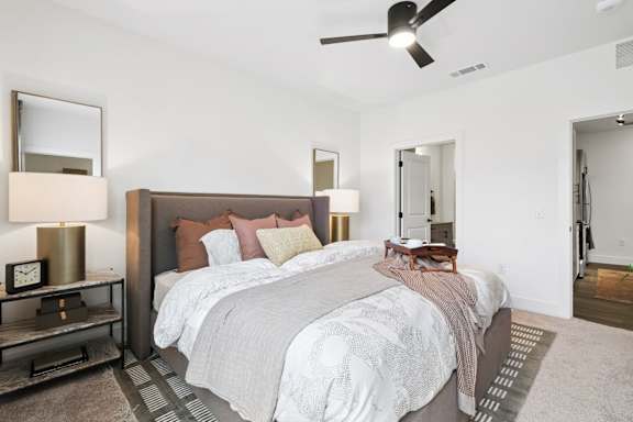 A bedroom with a large bed and a ceiling fan.