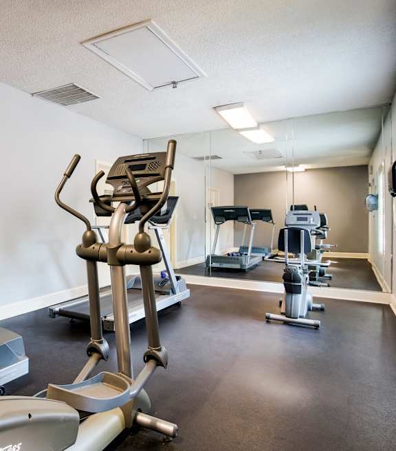 A gym with treadmills, elliptical machines, and other exercise equipment.
