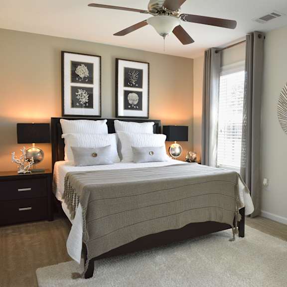 A bedroom with a bed, chair, and ceiling fan.