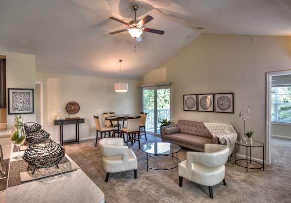 A living room with a white ceiling fan and a glass table.