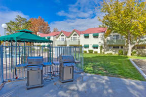 Outdoor BBQ Picnic Area with Grills, Gate, Grass and View of Pool