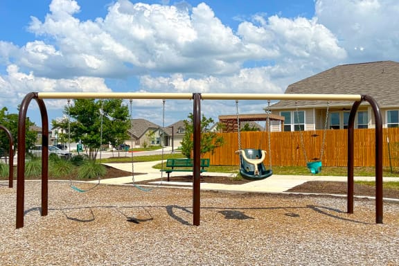 a swing set in a park with a house in the background