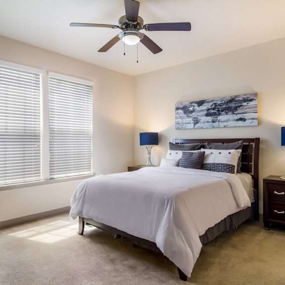 Model apartment bedroom with a bed and a ceiling fan at Oakleaf Plantation in Jacksonville, FL