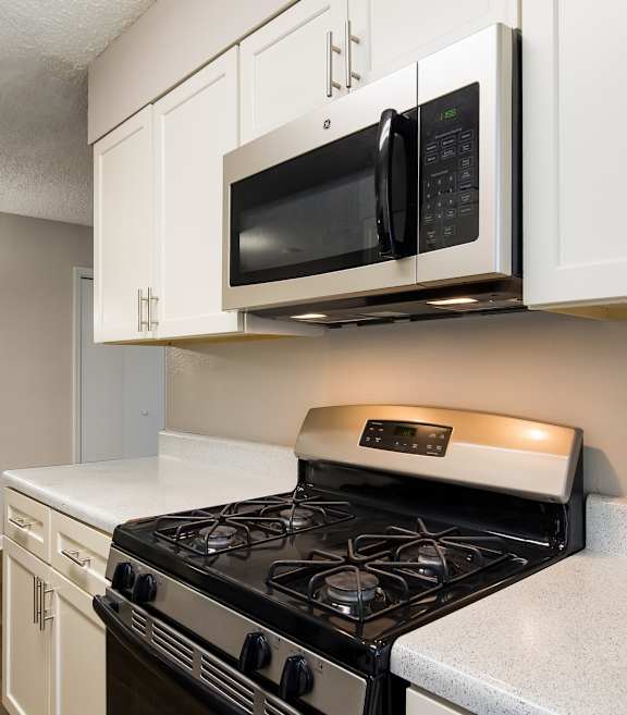 Beautiful kitchen with white cabinets and a black gas stove top oven at Dunwoody Pointe at Sandy Springs, GA