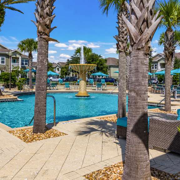 Community swimming pool with lush palm trees and fountain at Oakleaf Plantation in Jacksonville, FL