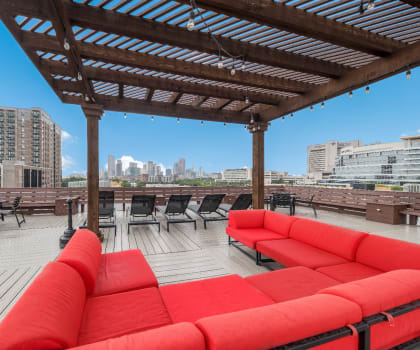 a rooftop deck with red couches and a pergola