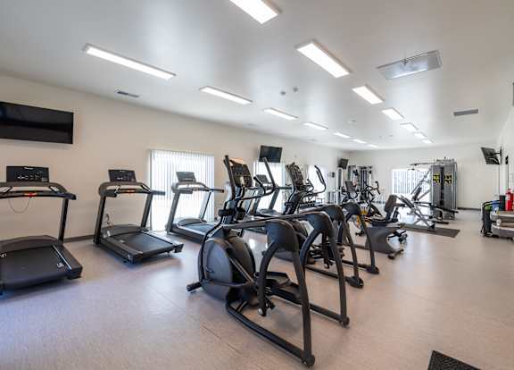 A gym with treadmills, elliptical machines, and other exercise equipment.