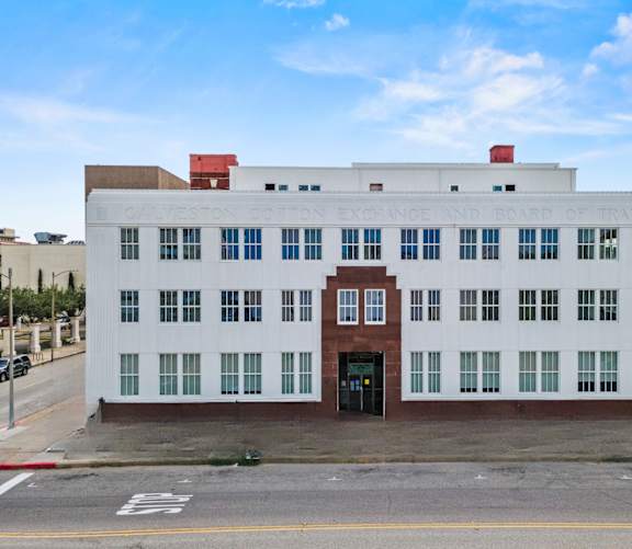 A white building with a red door and windows on the side.