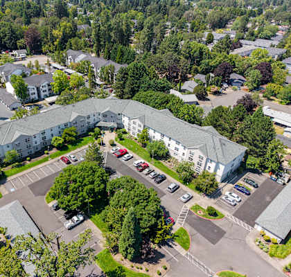 A large white building surrounded by trees and a parking lot.