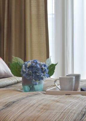 a bed with a tray and a vase of flowers on it