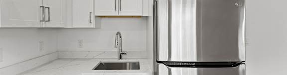 a white kitchen with a stainless steel refrigerator and sink