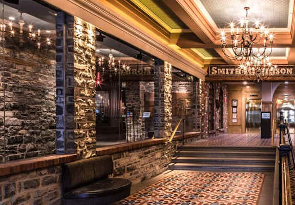 A long hallway with a brick wall and a chandelier hanging from the ceiling.