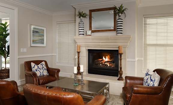 a living room with a fireplace and leather chairs