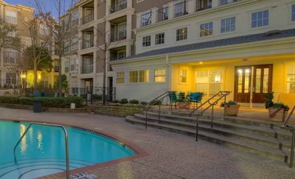 a swimming pool in front of an apartment building at night
