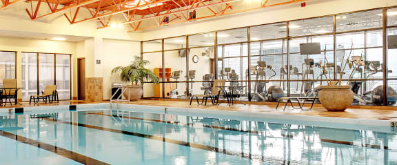 a large indoor swimming pool with chairs and a large vase on the side of the pool