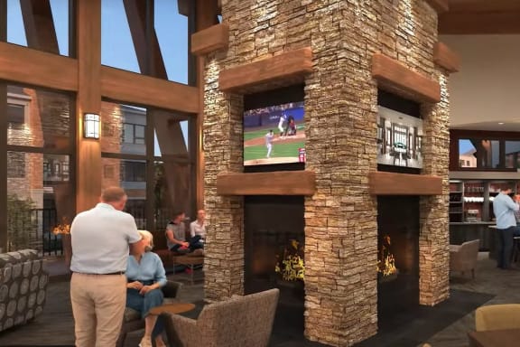 people watch a baseball game on a tv in a lobby with a fireplace