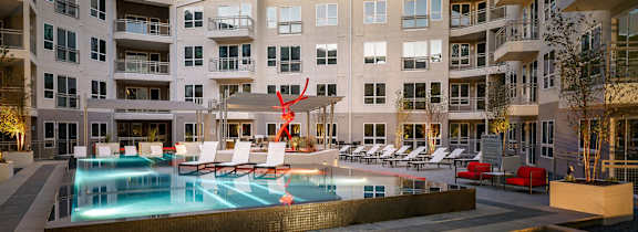 an apartment building with a pool and lounge chairs