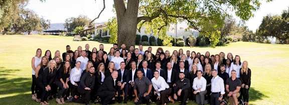 A group of people are gathered in a park for a photo.