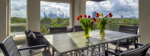 a beautiful rooftop patio with two vases of tulips on a table overlooking the downtown cityscape