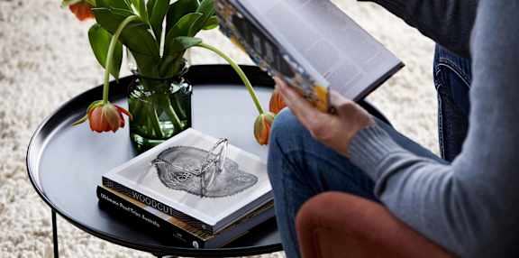 A person is reading a book with a heart-shaped bookmark.