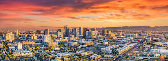 A cityscape with buildings and roads under a colorful sky.