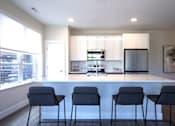Thumbnail 16 of 28 - A modern kitchen with a bar area and chairs.