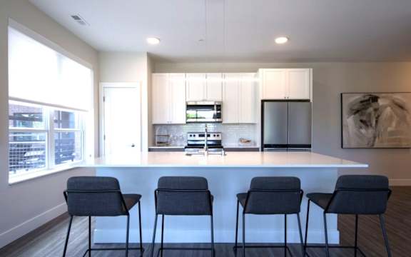 A modern kitchen with a bar area and chairs.