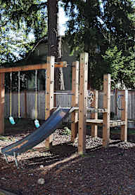 A wooden playground with a green slide.