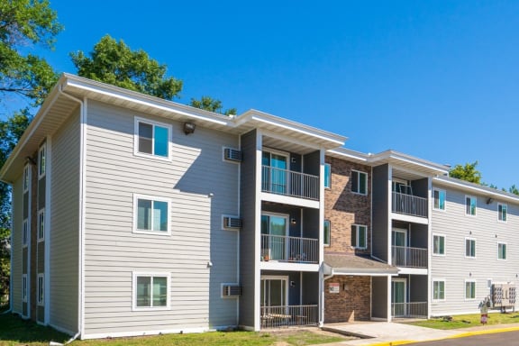 an apartment building with white siding and a brick facade