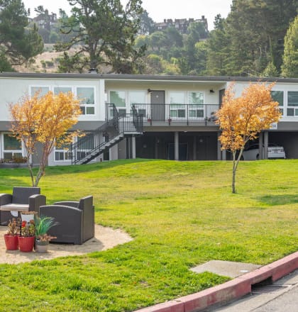 a building with a lawn and chairs in front of it at Trailhead Apartments at Tam Junction, Mill Valley