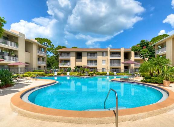 A large swimming pool is surrounded by apartment buildings.