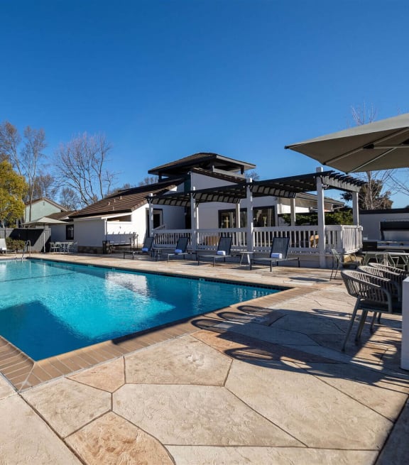 a swimming pool with chairs and umbrellas at Diablo Vista Apartments, Livermore, CA