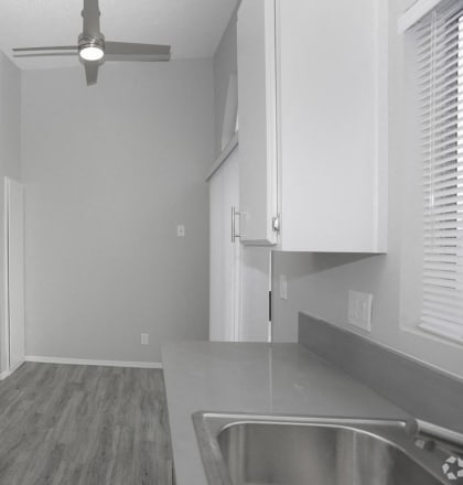 an empty kitchen with white cabinets and a ceiling fan at The Marq Apartments LLC, California