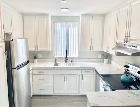 a white kitchen with stainless steel appliances and white cabinets at The Flats on Addison, California