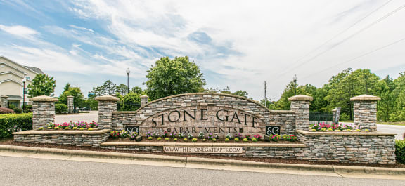 a stone gate sign with flowers in front of it at Stone Gate Apartments, Spring Lake, North Carolina