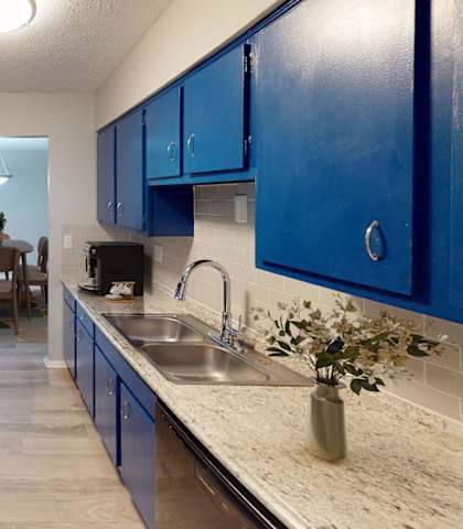 A kitchen with blue cabinets and a marble countertop.