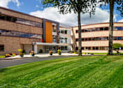 Thumbnail 13 of 21 - A modern building with a curved glass facade and a brown exterior.