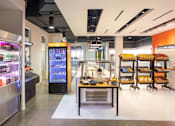 Thumbnail 1 of 21 - A modern cafe with a variety of drinks and snacks on display.