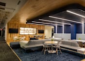 Thumbnail 10 of 21 - A modern lounge area with a wooden ceiling and blue carpet.