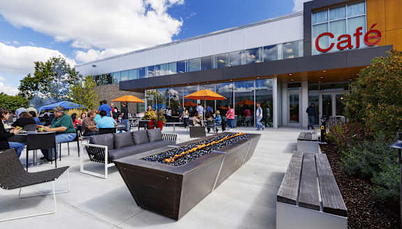 A modern cafe with people sitting at tables outside.