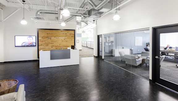 A modern office space with a wooden reception desk and glass walls.