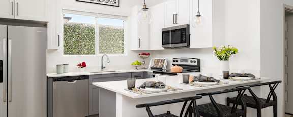 A modern kitchen with a white countertop and grey cabinets.