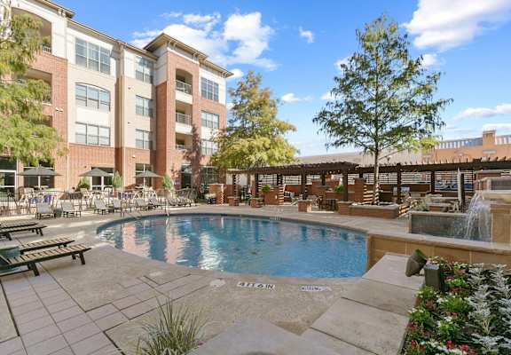 A large pool surrounded by a patio area with a building in the background at Prairie Crossing, Farmers Branch, Texas