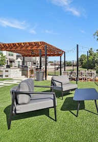 A patio with a wooden pergola and a fireplace.