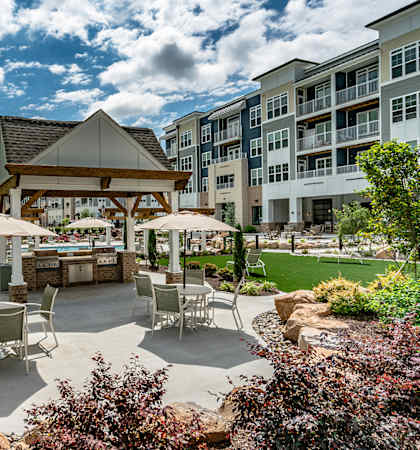 an outdoor patio with tables and umbrellas in front of an apartment building