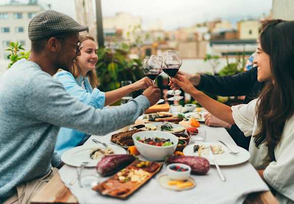 People toasting with wine glasses at a table full of food.